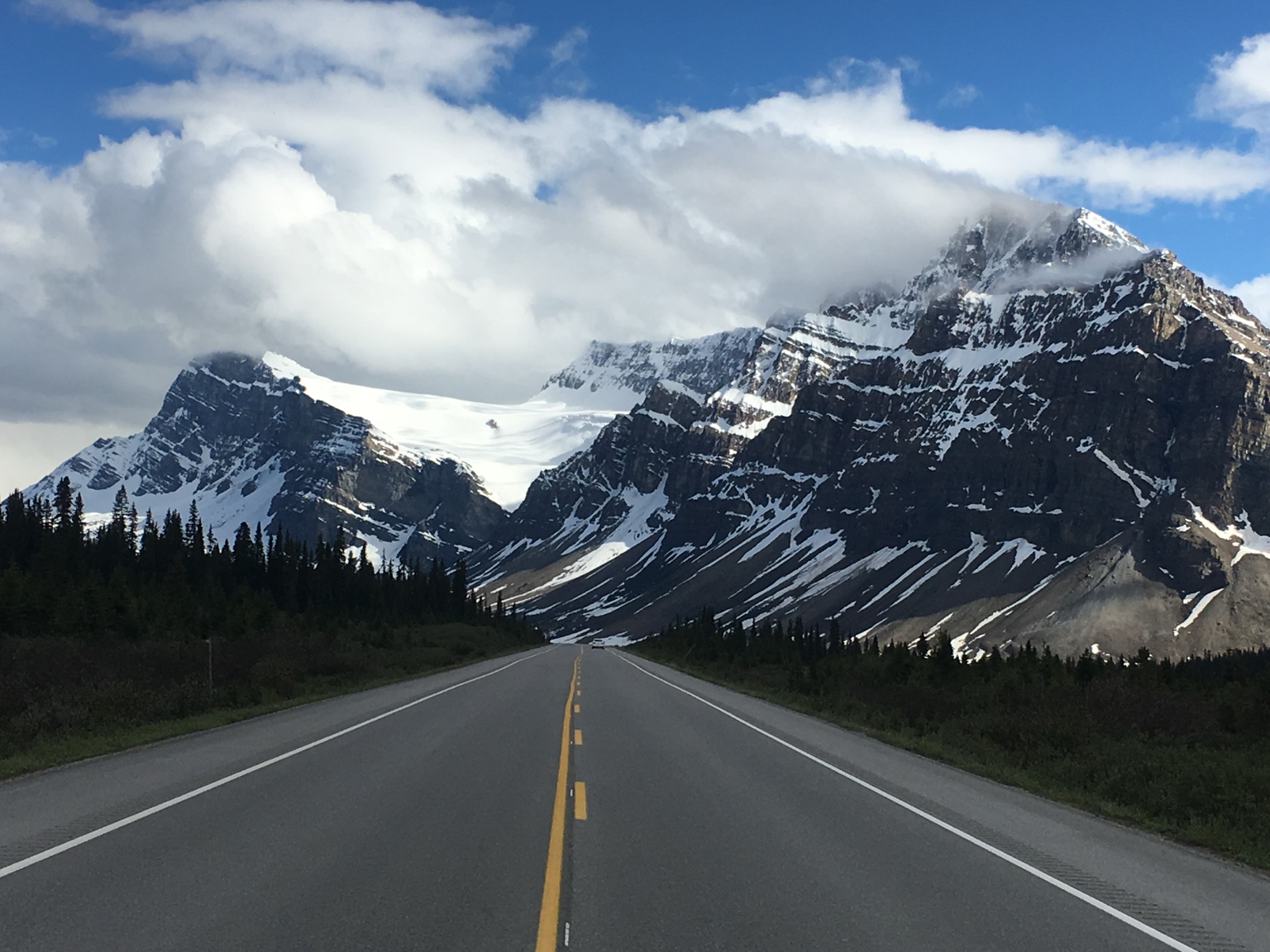 A road leading toward snow-covered peaks in the Canadian Rockies
