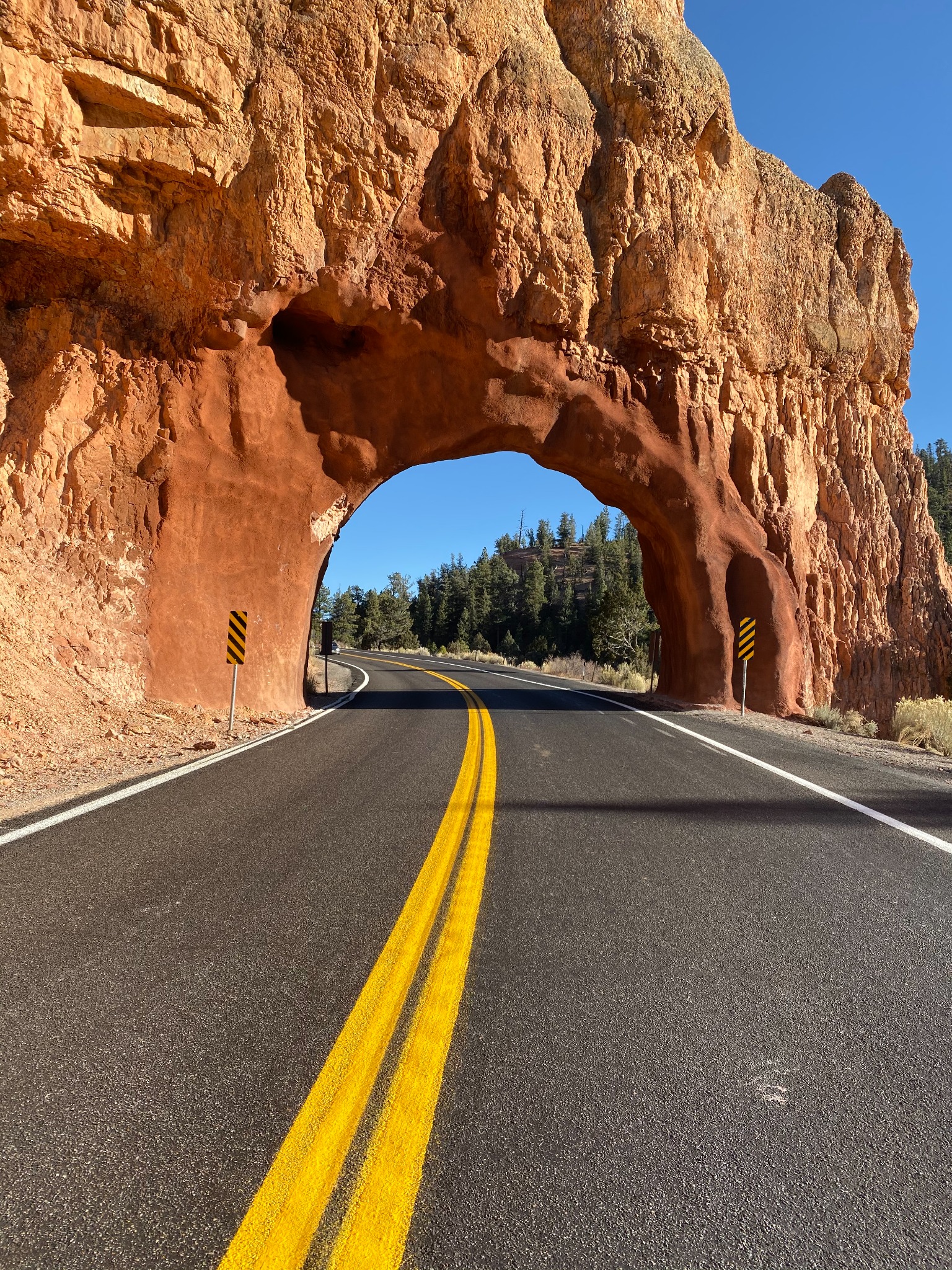 A highway passing through a red-rock arch in Utah